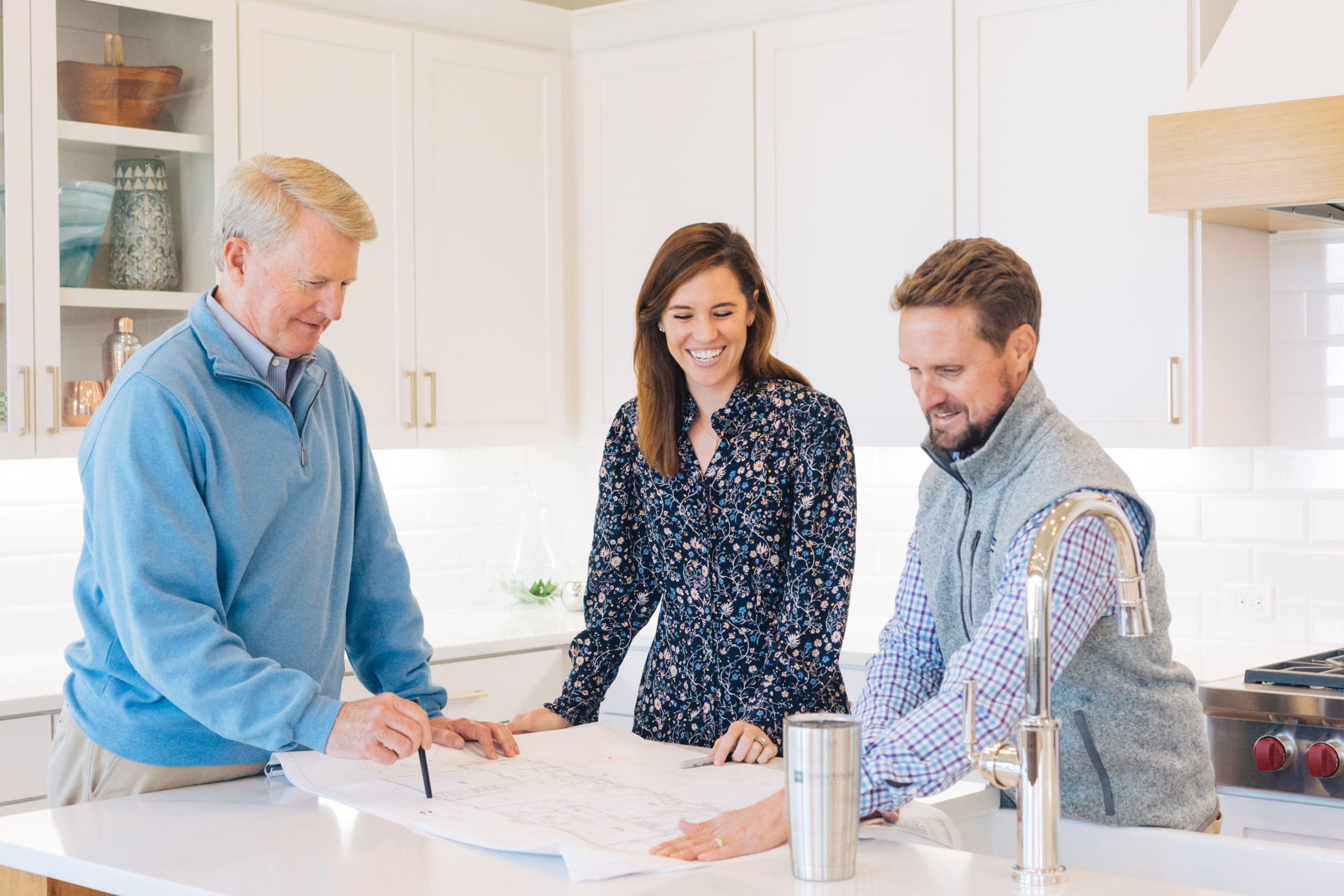 photo of John Hawkins, Kelly and James working and looking at floorplan or layout on kitchen counter team working in luxury home dallas texas